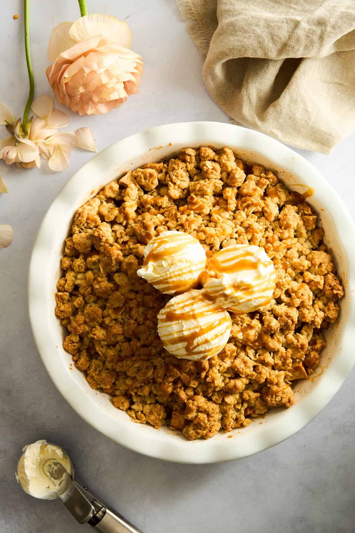 Apple crisp topped with vanilla ice cream and caramel sauce.