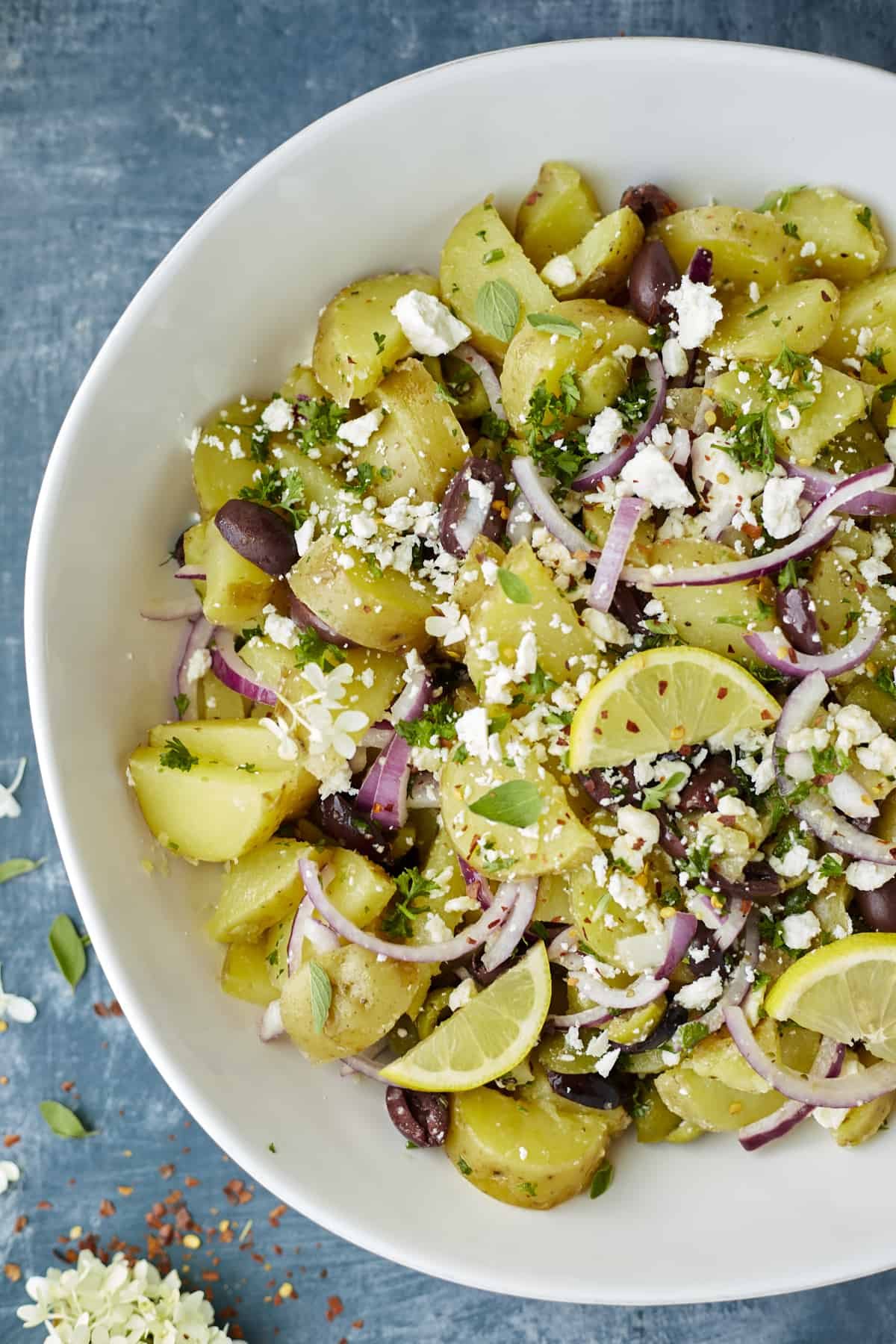 A bowl of Lemon Greek Potatoes with red onions, feta cheese, and fresh herbs.