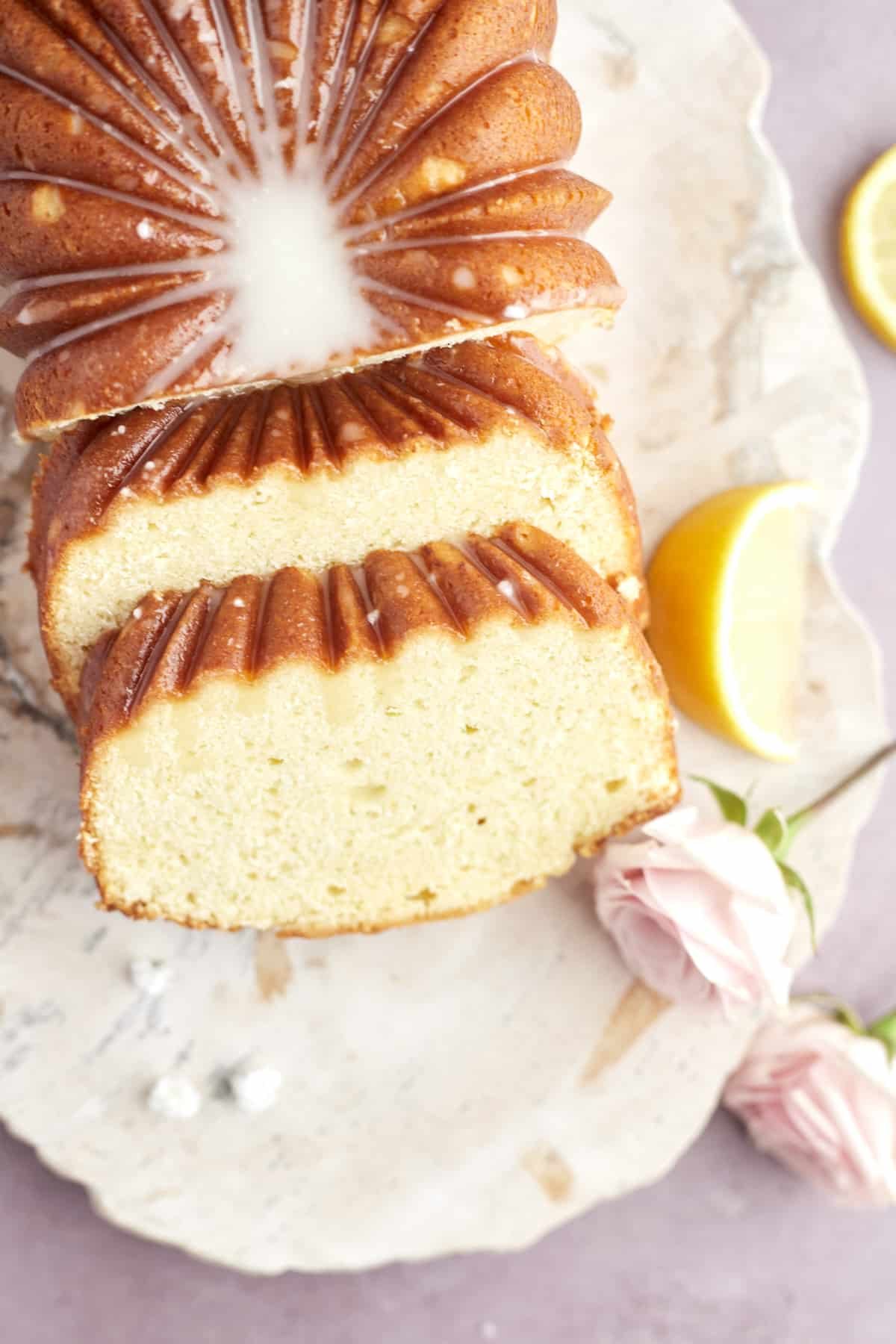 A glazed lemon loaf with two slices cut.