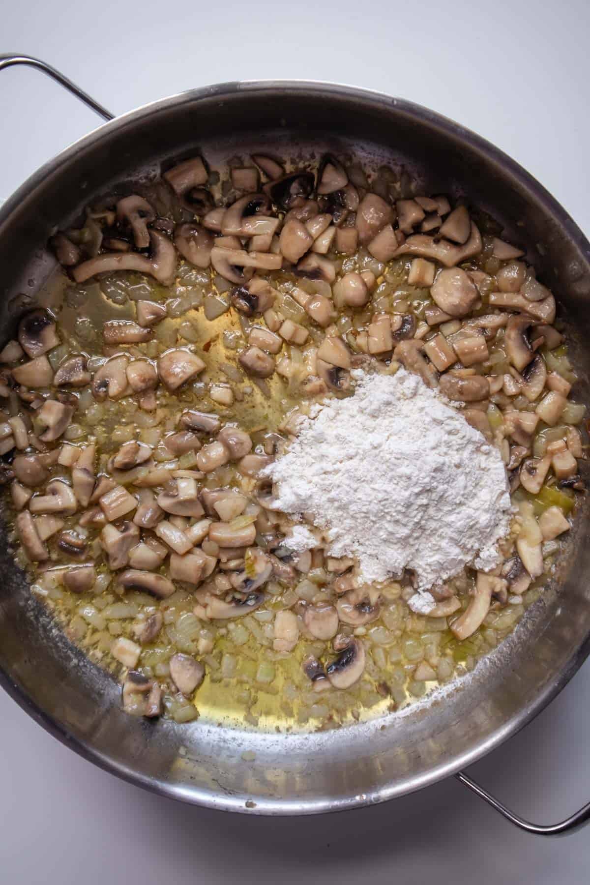 onions, mushrooms, and butter in a pot with flour on top.