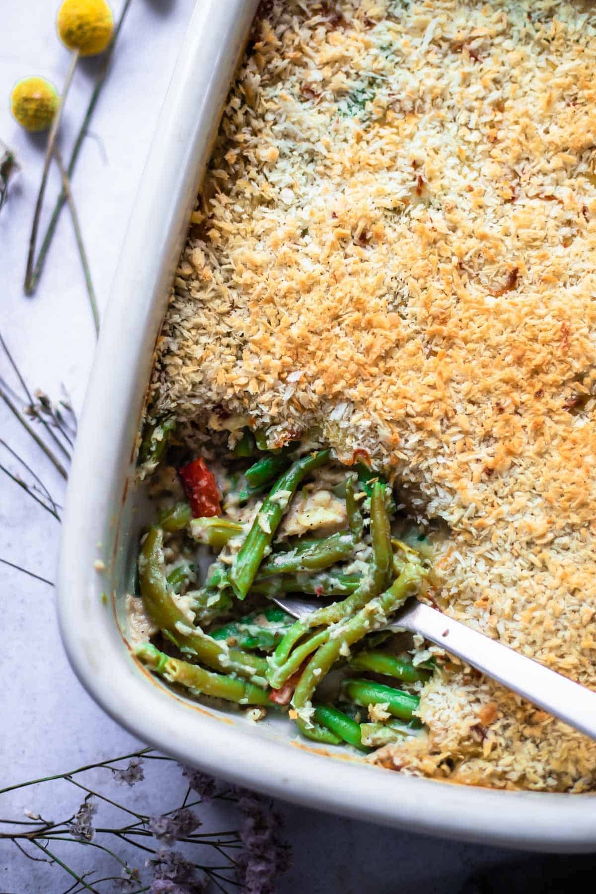cheesy green beans topped with panko breadcrumbs in a white baking dish.