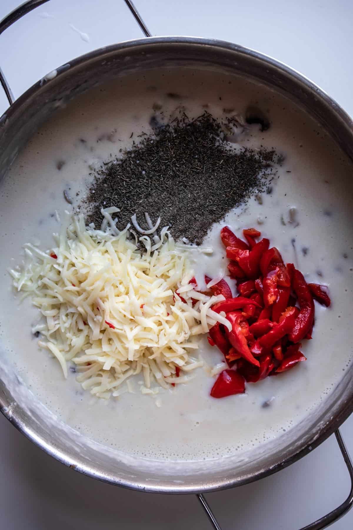cheese, pimentos, and seasonings being stirred into roux.