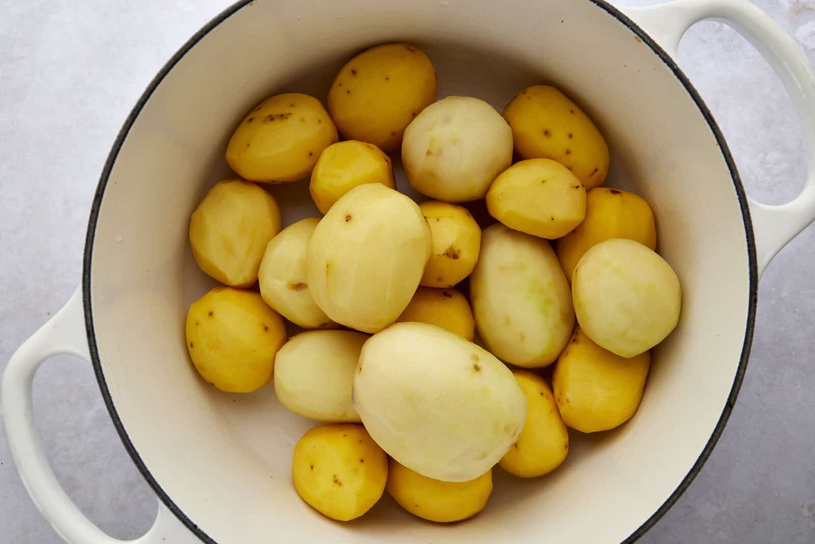 Peeled white and yellow potatoes in a large pot.