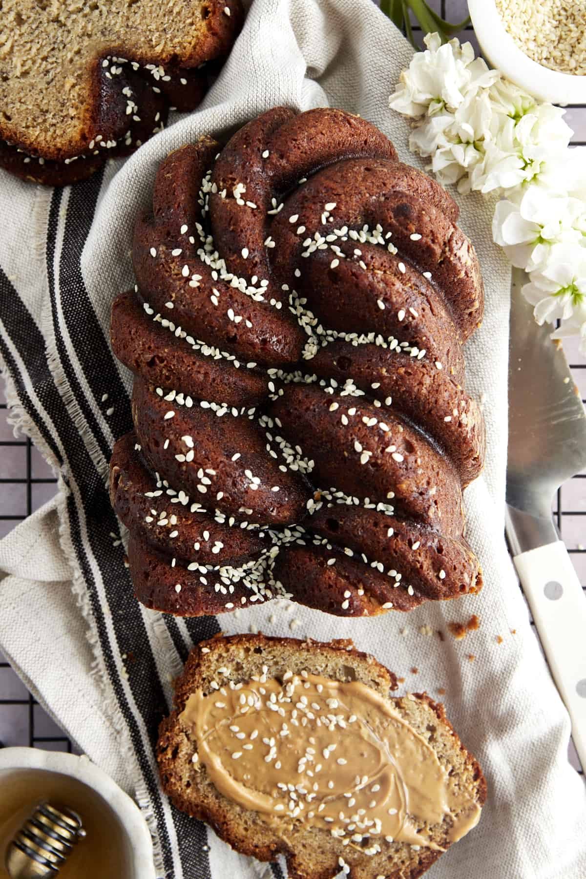 A loaf of tahini banana bread with a slice next to it topped with nut butter.