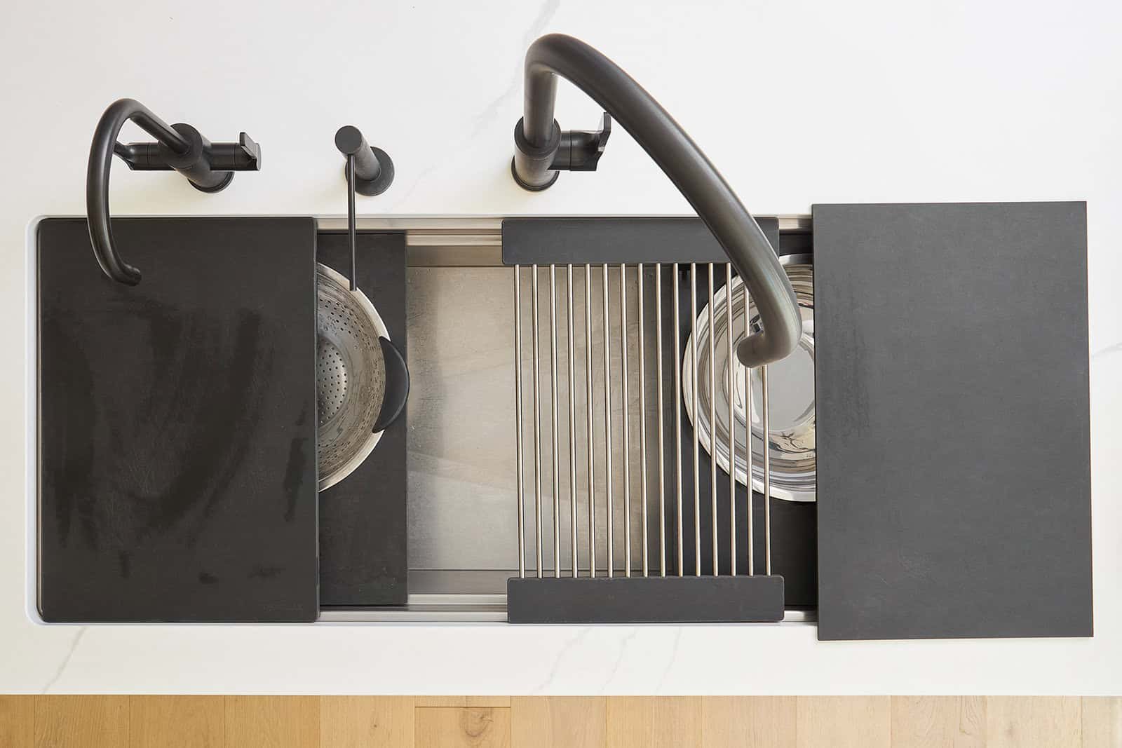 Overhead image of a kitchen sink with various attachments for cutting boards and wire racks.