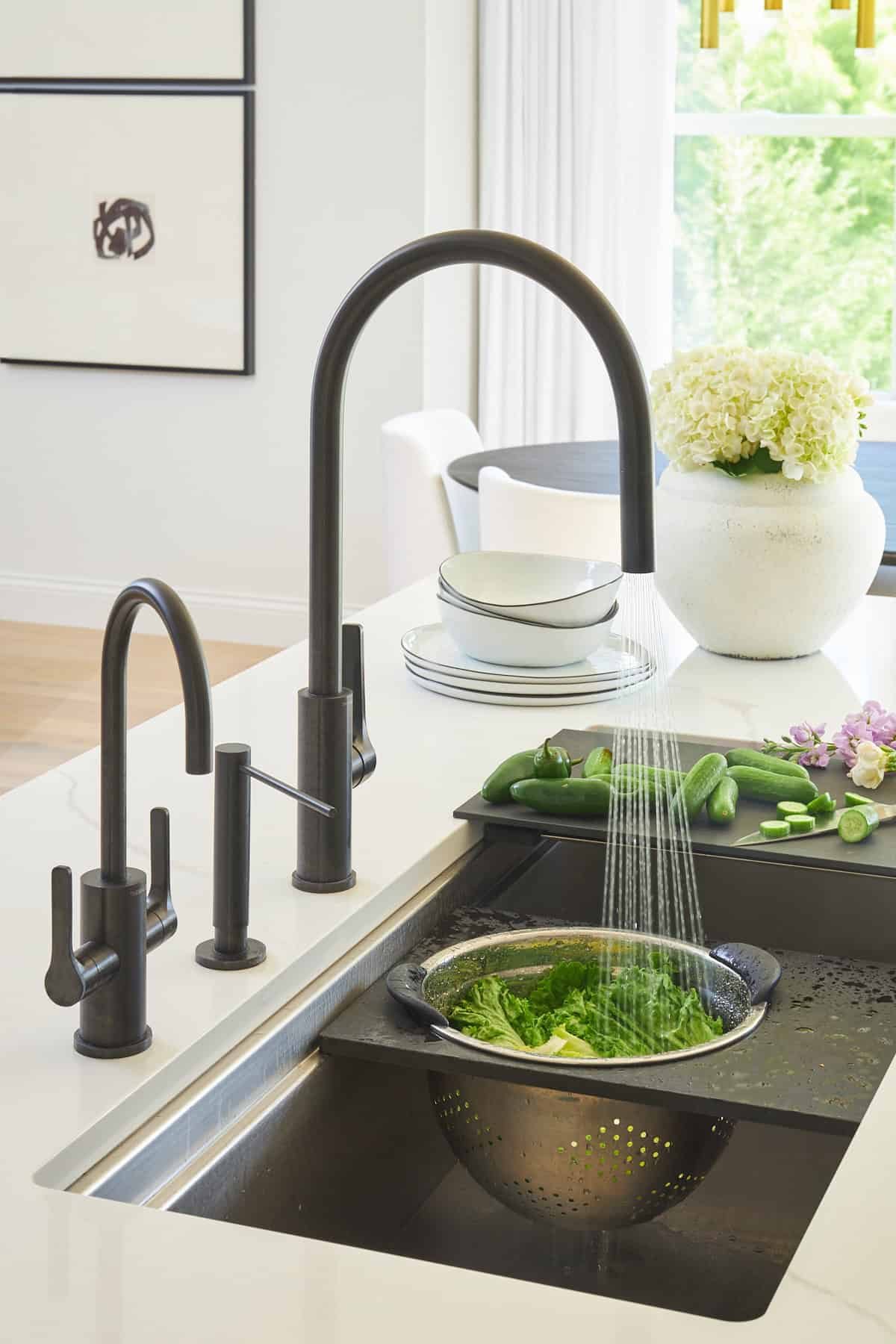 A colander attachment on a sink full of lettuce being rinsed.