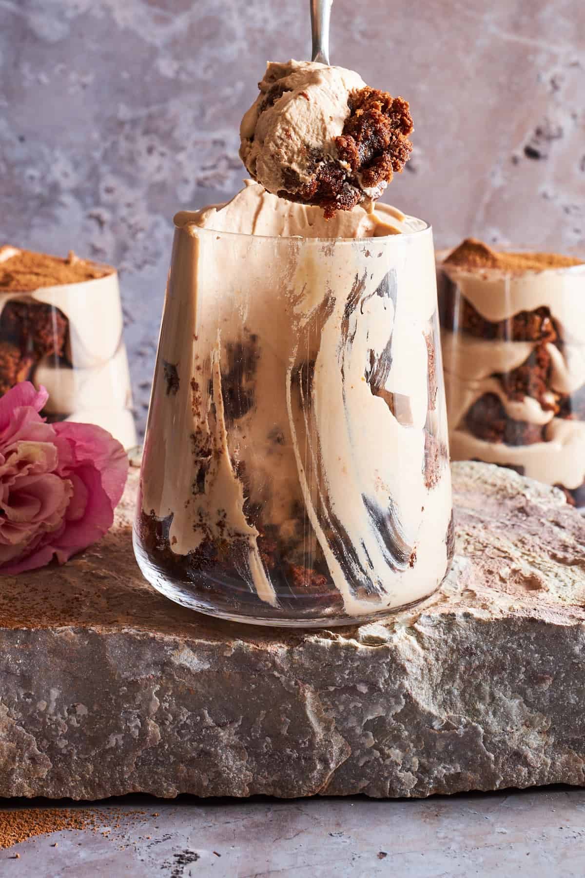 A spoon lifting a bite of tiramisu brownie parfait from a cup.