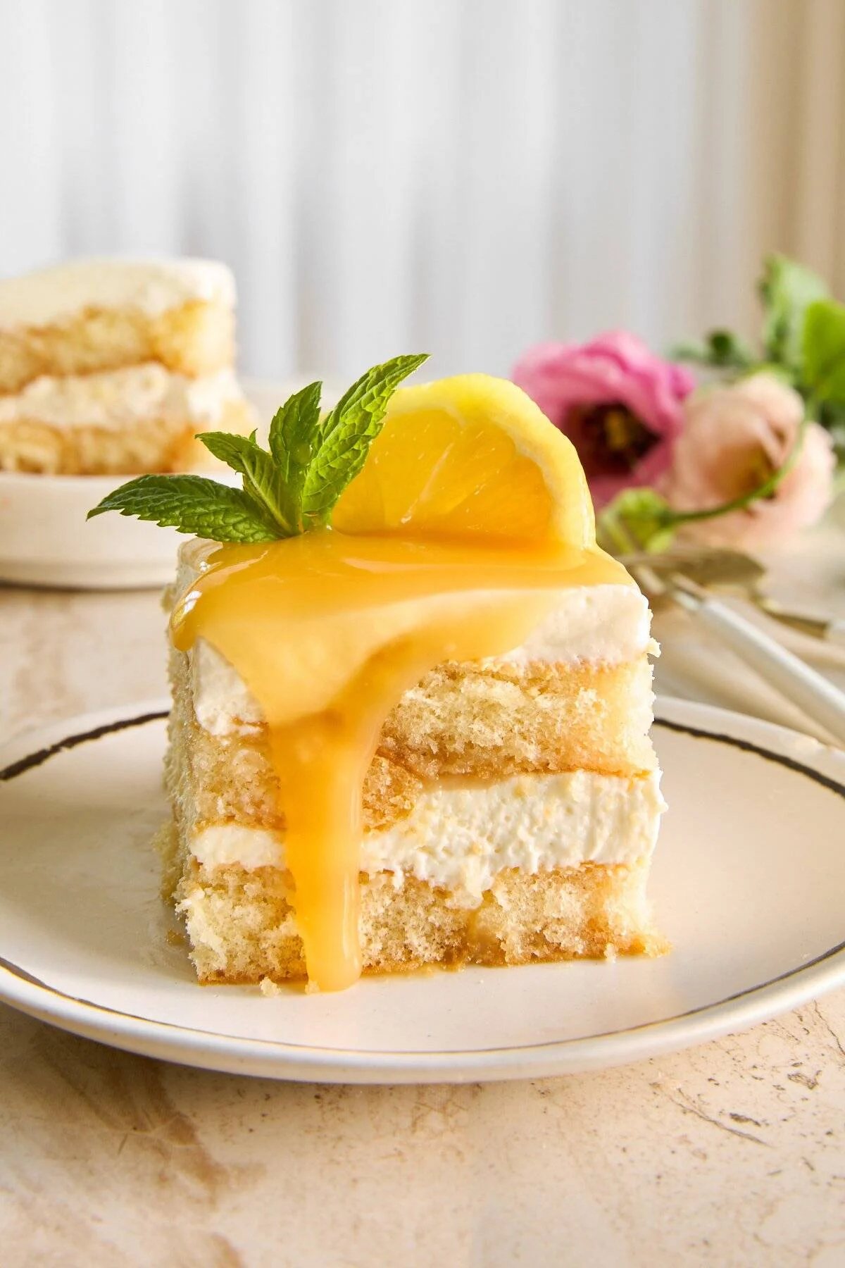 A slice of lemon tiramisu topped with lemon curd on a white plate.