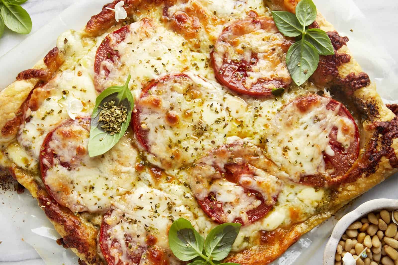 Baked tomato pesto puff pastry topped with fresh basil.