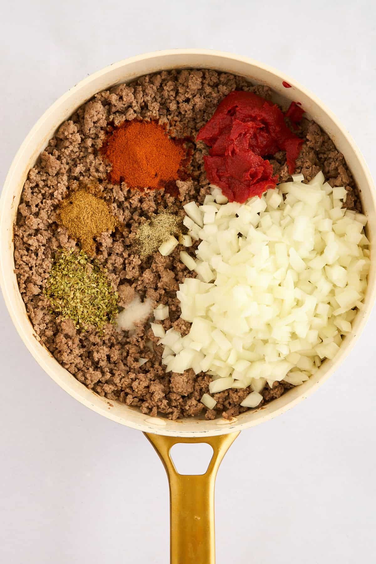 Ground beef, spices, and onions in a pot.