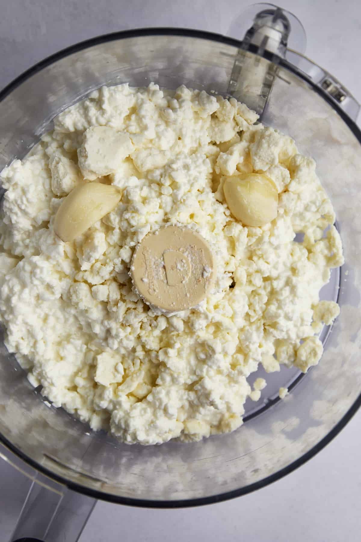 Cottage cheese, feta, and garlic cloves in a food processor.