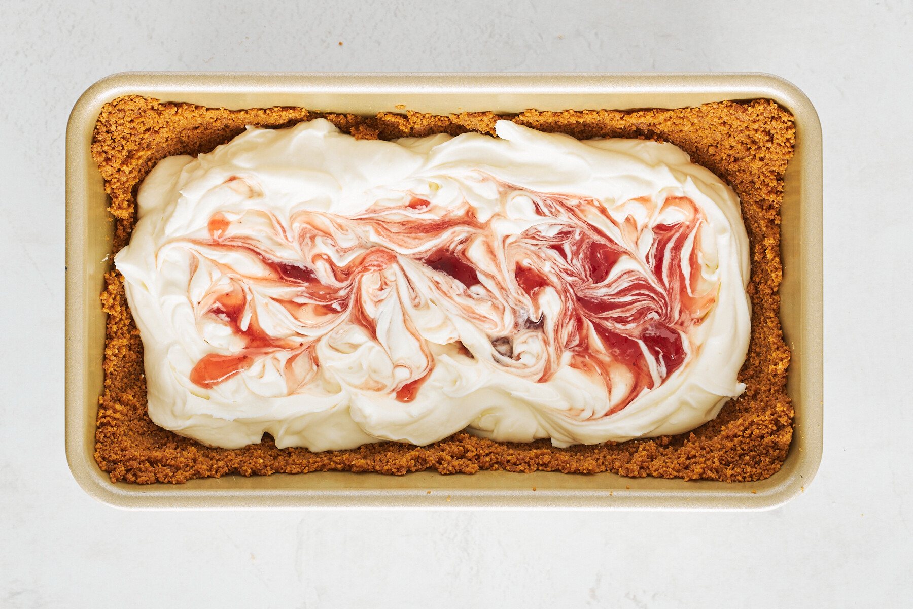 Biscoff crust filled with cream cheese filling swirled with strawberry preserves.