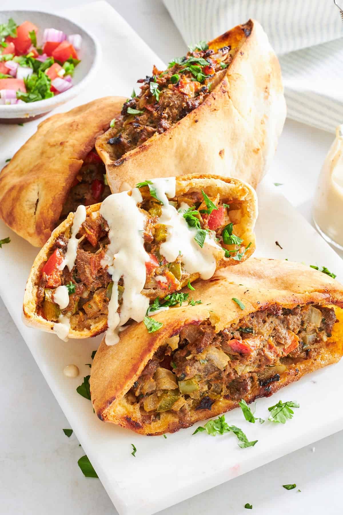 Four hawashi pita pockets on a plate.
