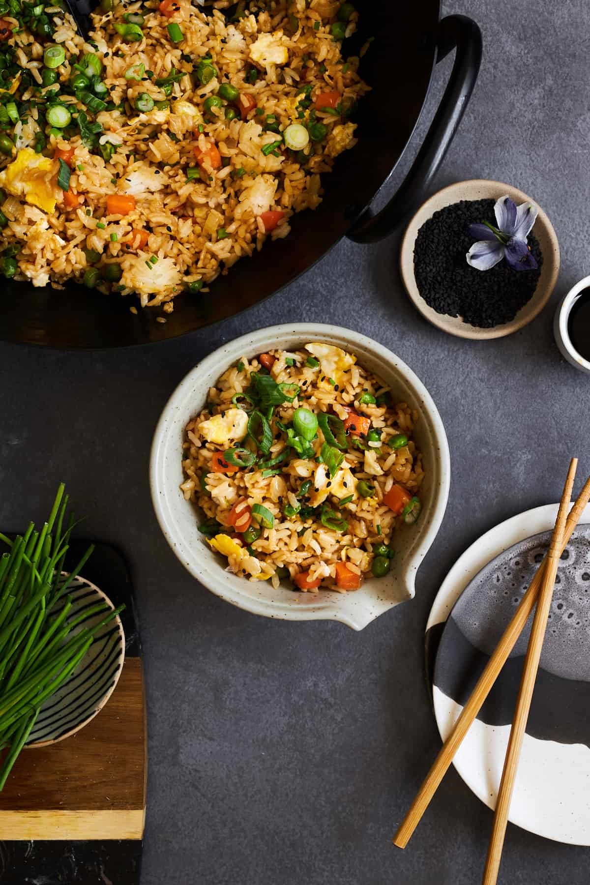 A bowl of wok fried rice next to a pot.