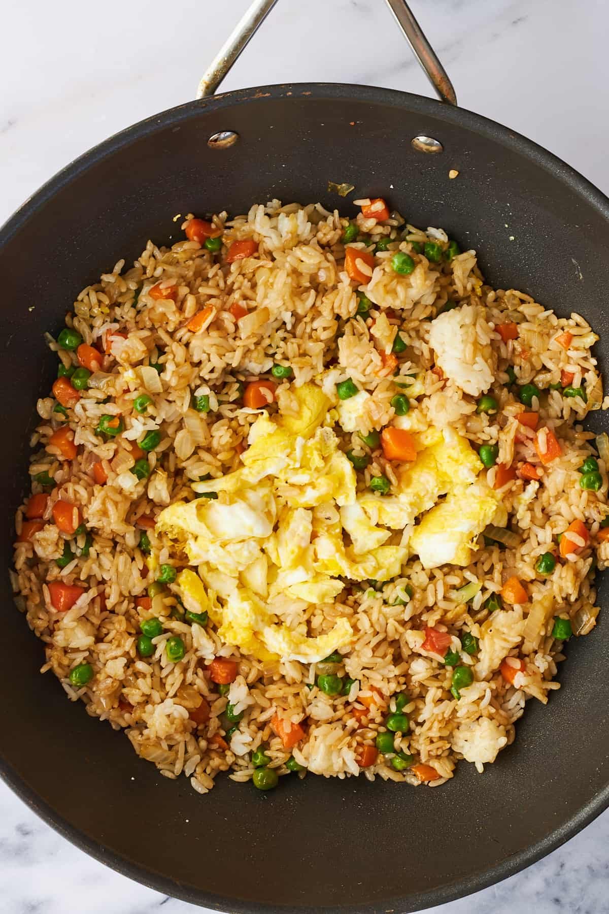 Scrambled eggs being added to wok fried rice.
