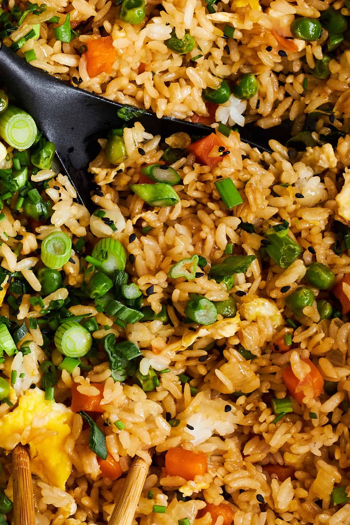Close up image of wok fried rice topped with green onions.