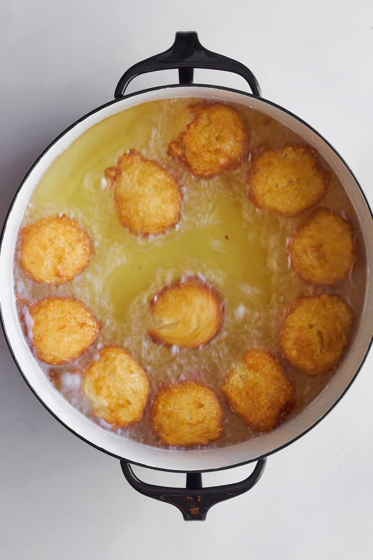 Zeppole donuts frying in a pot.