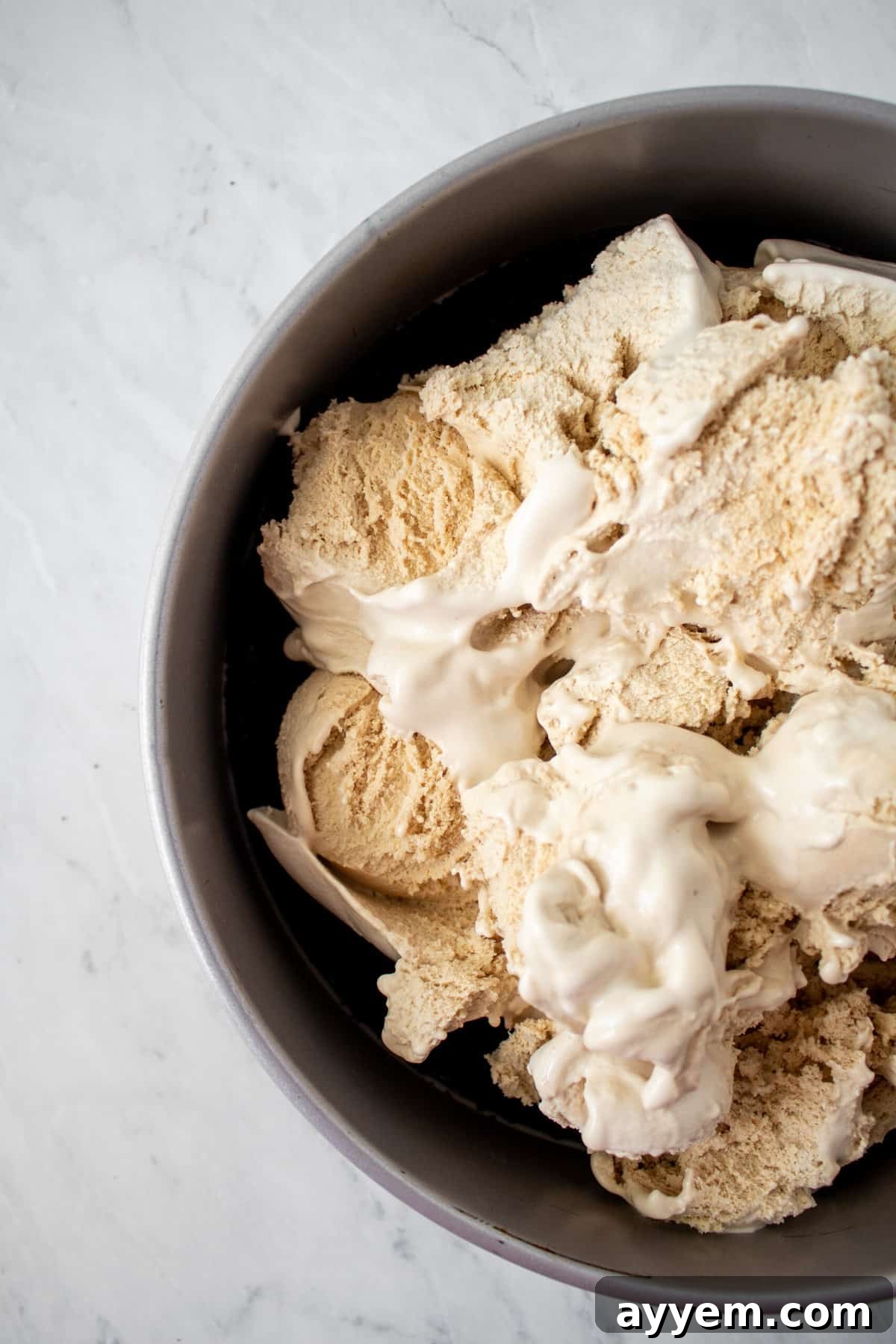 Generous scoops of creamy coffee ice cream placed on top of a chocolate cookie crust, awaiting the next delicious layer of the pie.