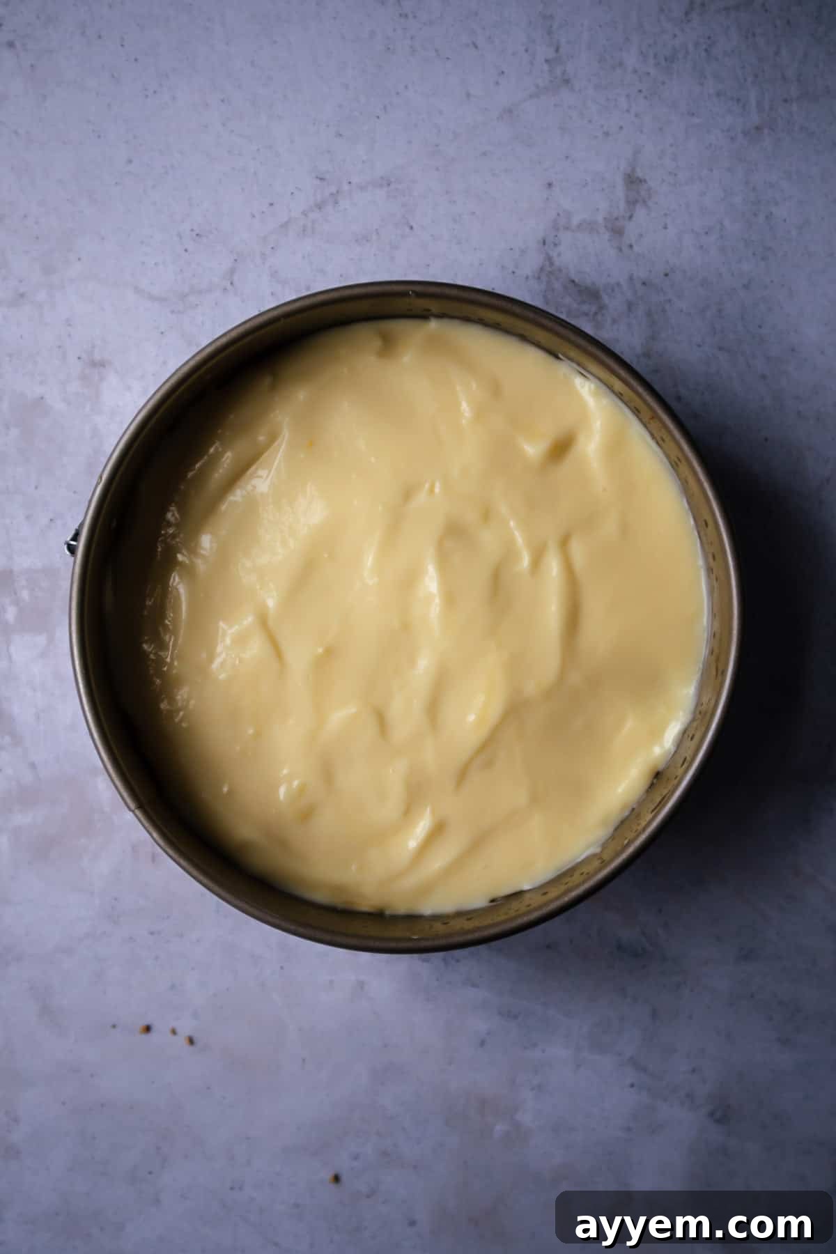 A smooth, pale yellow layer of vanilla pudding spread over banana slices and dulce de leche, creating a delightful intermediate layer in the banoffee pie.