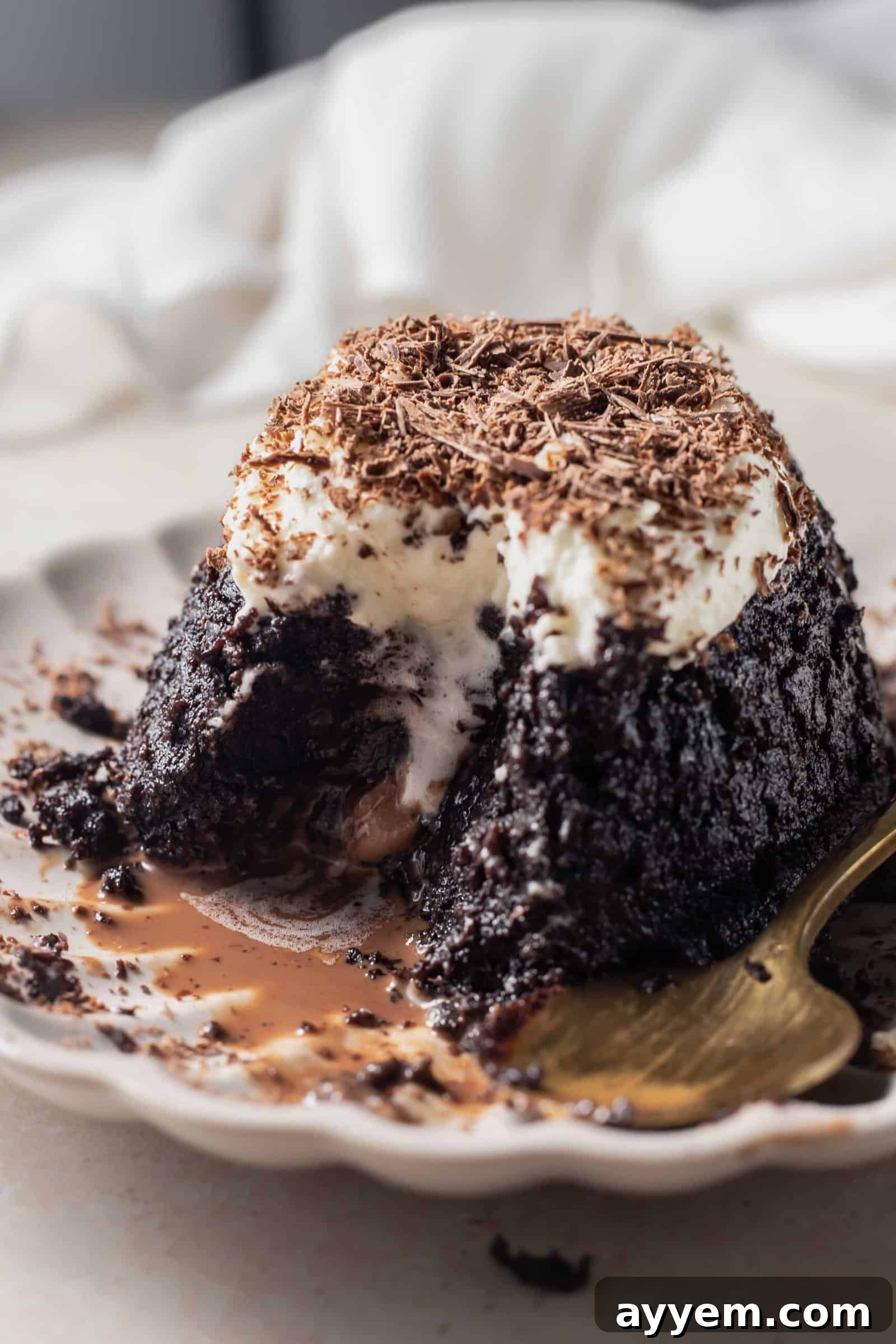 A close-up of a hazelnut chocolate lava cake, with a bite taken, clearly showing the luscious molten chocolate interior spilling out.