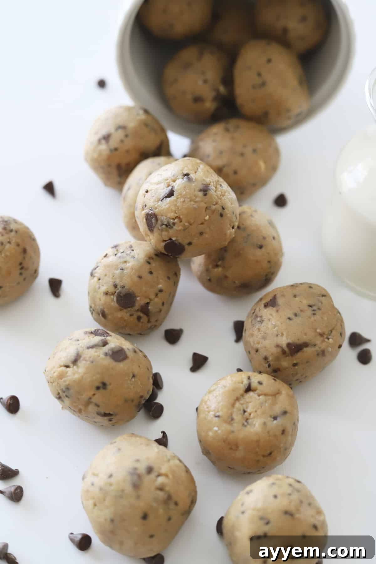 A close-up shot of a cup overflowing with deliciously rich peanut butter energy balls, generously adorned with chocolate chips. These easy, no-bake treats are proudly refined sugar-free, gluten-free, and dairy-free, making them an ideal healthy snack.
