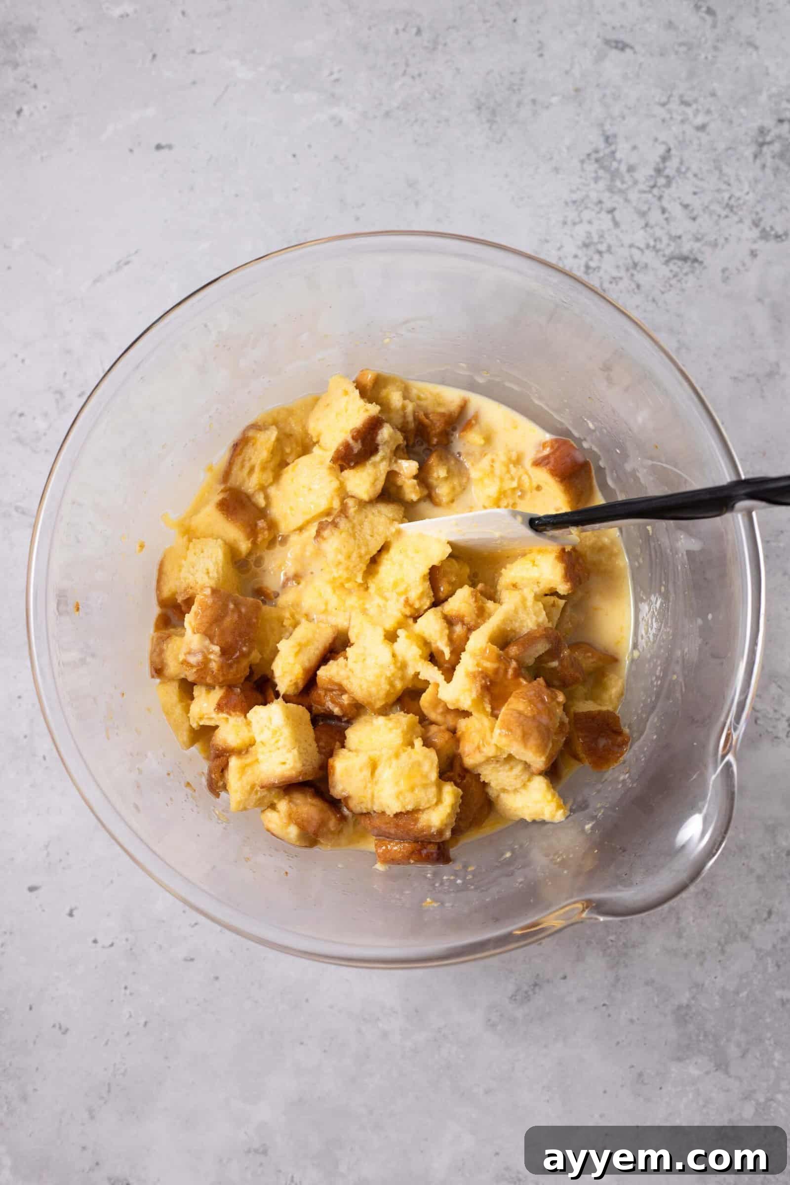 bread pieces being combined with egg yolks, whole milk, sweetened condensed milk, and sugar