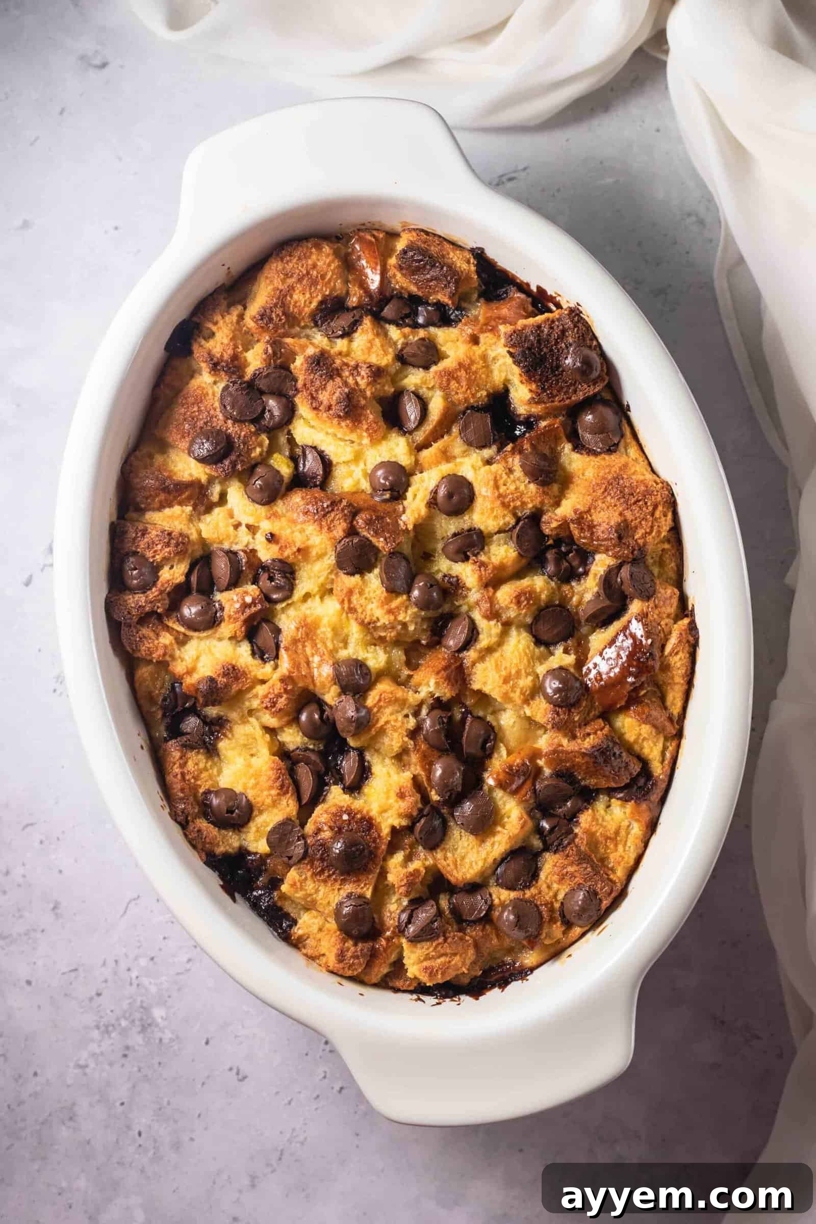 an oval dish full of baked tres leches bread pudding topped with chocolate chips
