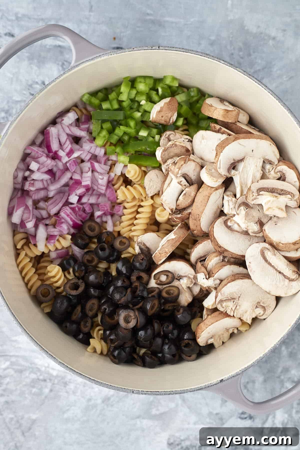 Pizza Night Pasta Pot 3 overhead image of a pot full of uncooked pasta, red onions, green peppers, mushrooms, and black olives