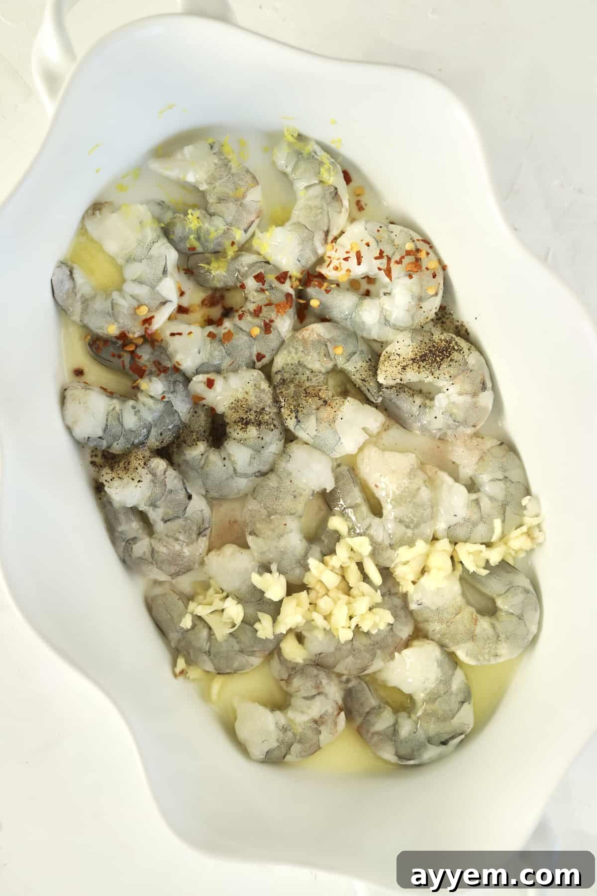Golden Garlic Shrimp Bake 3 raw shrimp in a baking dish with herbs, garlic, and lemon juice