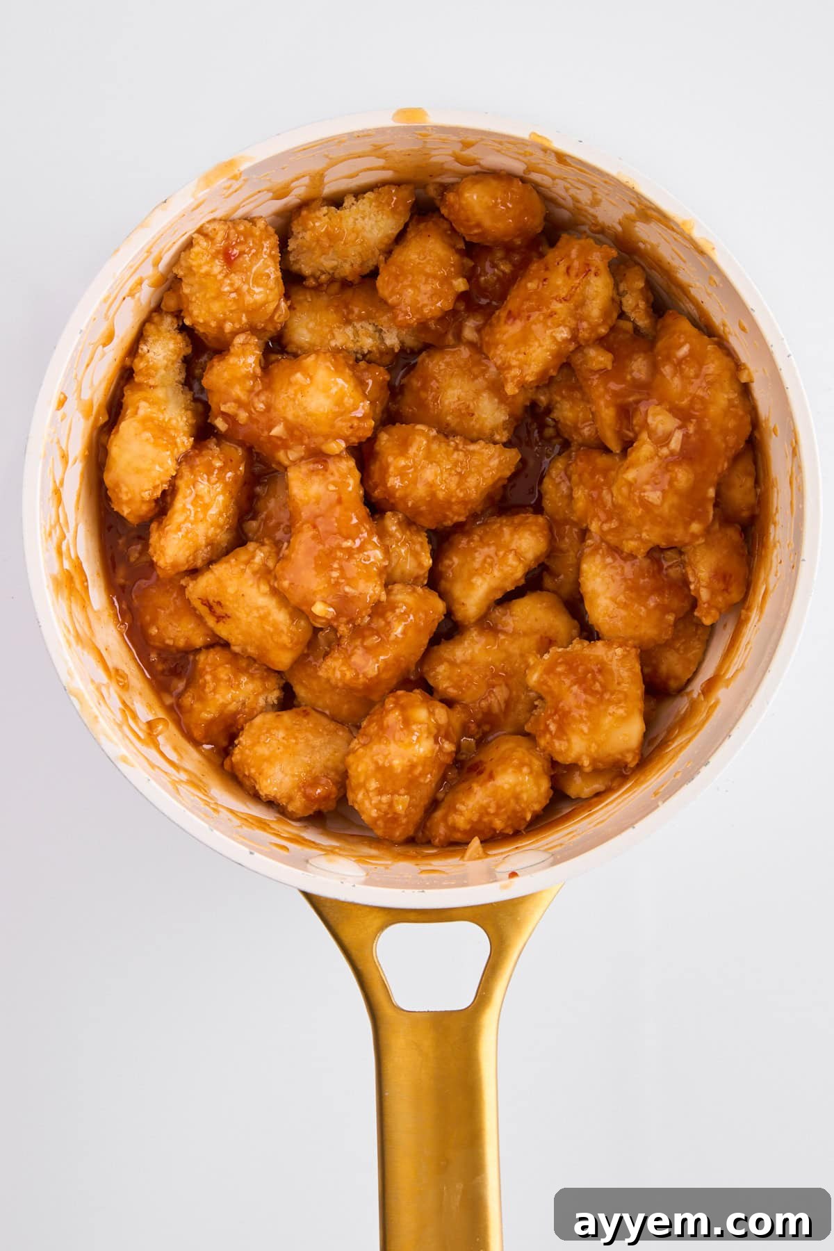 Finished orange chicken in a pot, coated in glossy sauce.