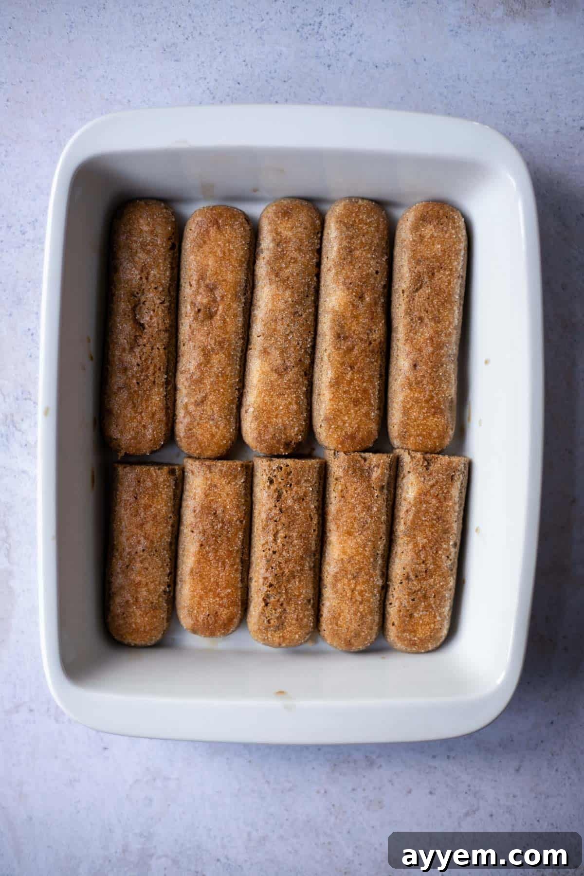 Ladyfingers neatly arranged in a baking dish, ready to be soaked in coffee for the tiramisu layers.