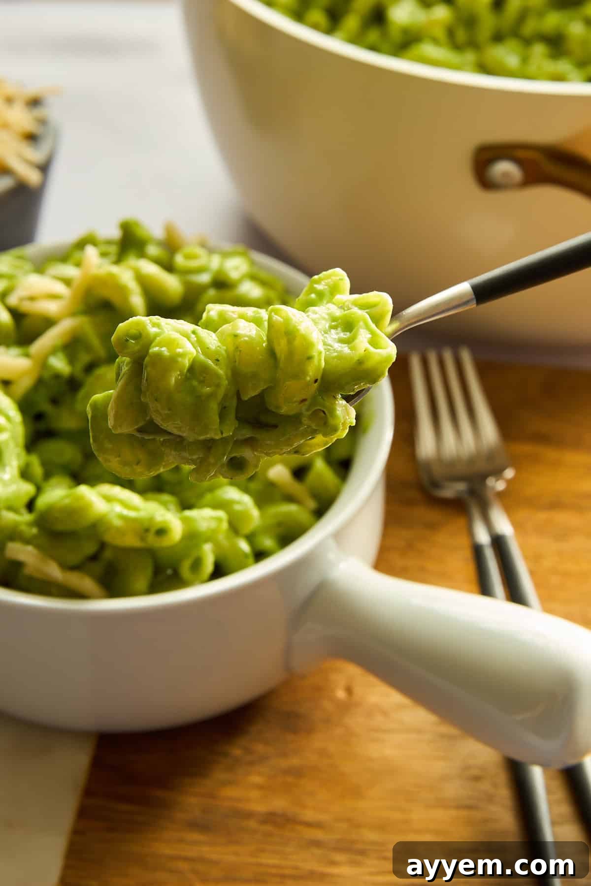 A close-up of a serving of green mac and cheese, highlighting its creamy texture and fresh, vibrant color.