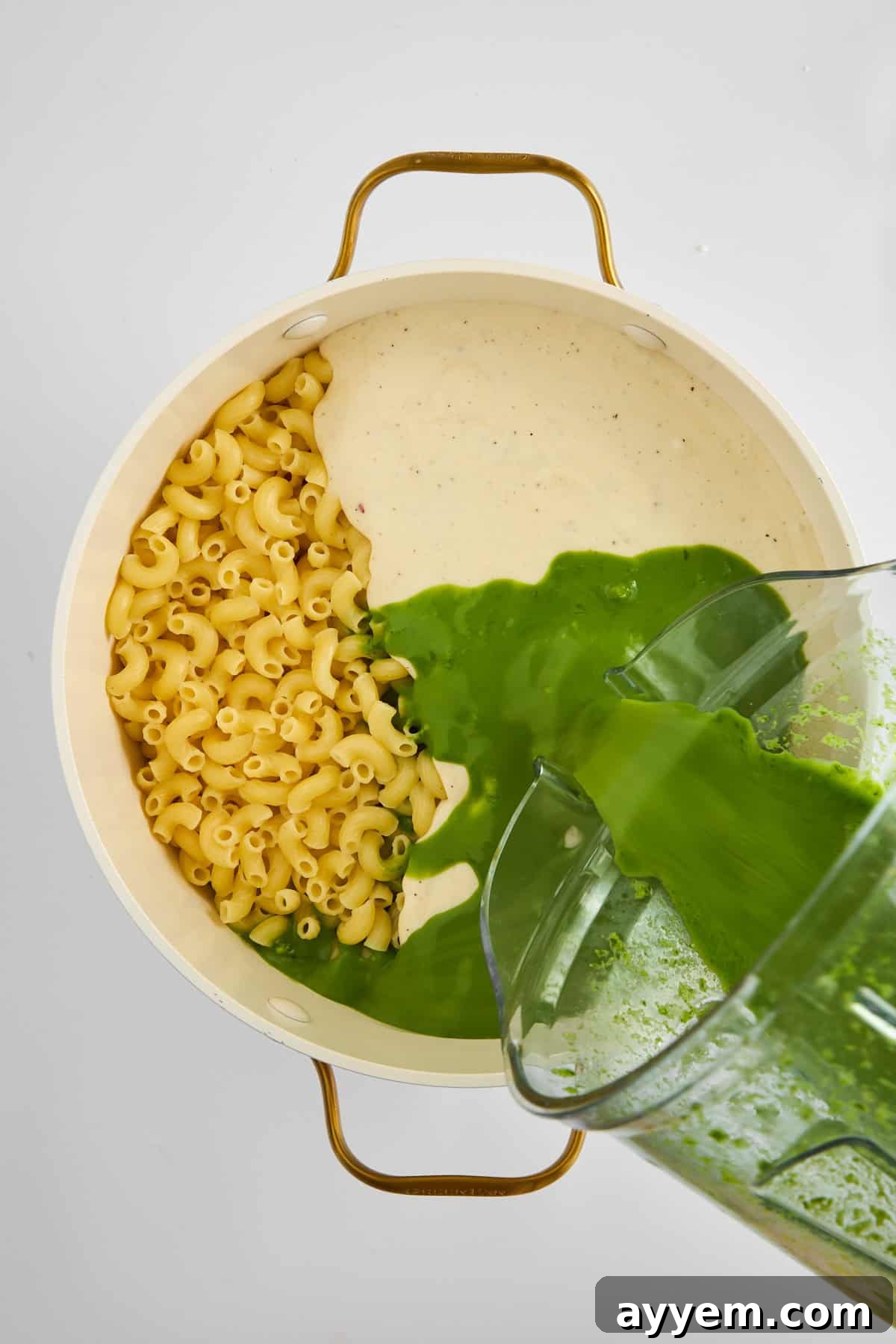 The rich, green cheese sauce being prepared in a large pot.