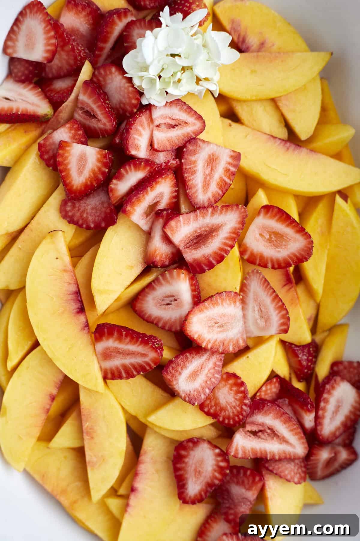 Fresh peaches and strawberries arranged beautifully in a baking dish, ready for the cobbler preparation.