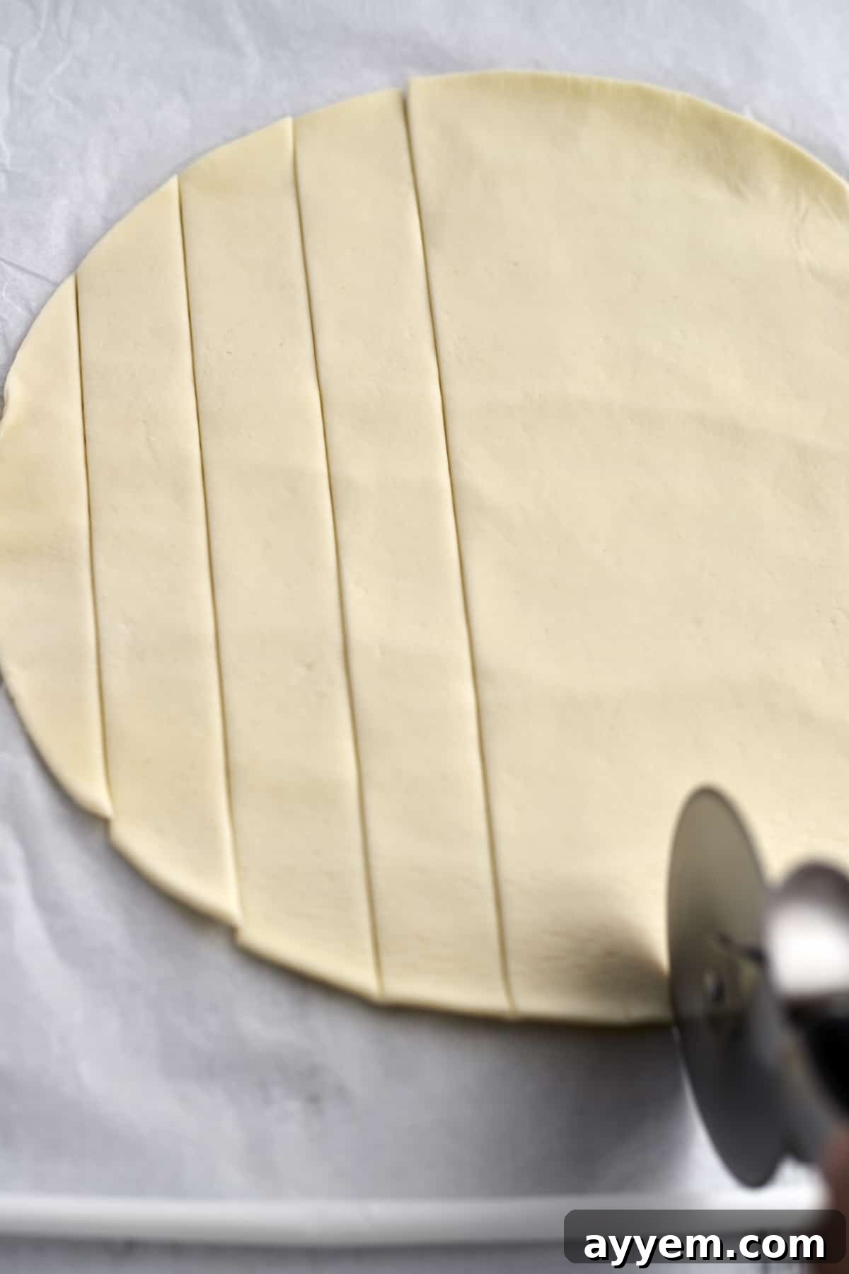 Cobbler dough being sliced into uniform strips on a cutting board, preparing for the topping.