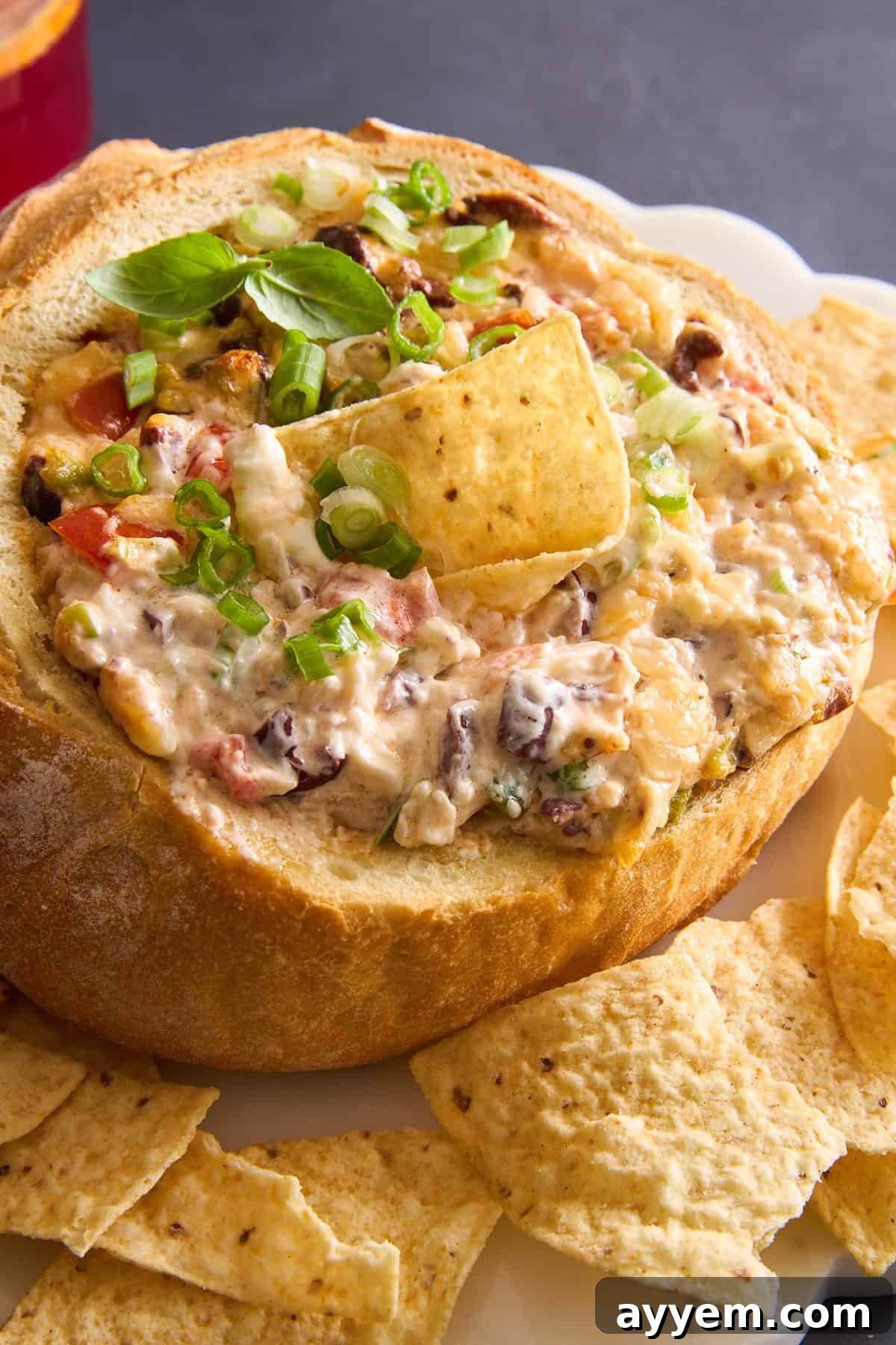 A sourdough bread bowl cheese dip bowl with a tortilla chip sticking out, showcasing the melted cheese and a perfect serving suggestion.