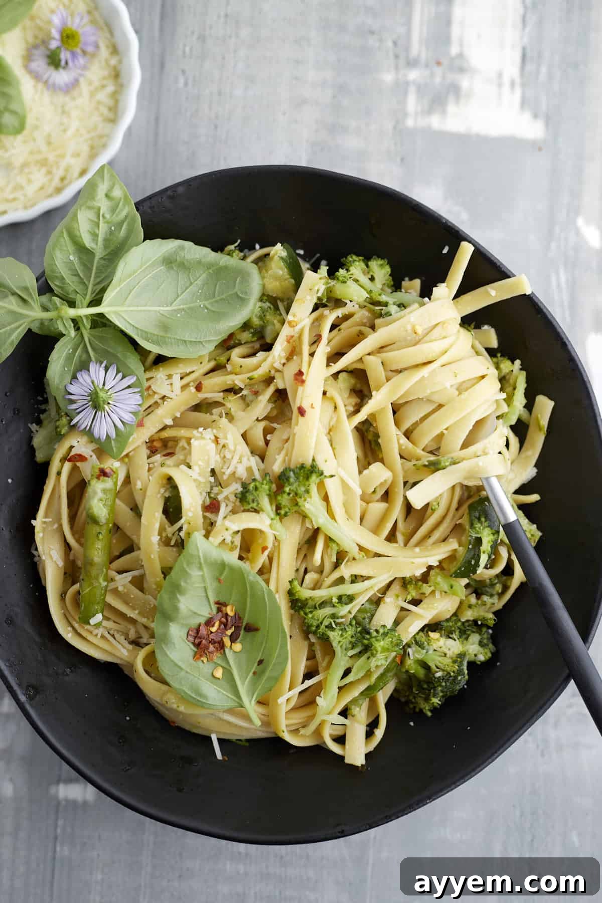 A black bowl of one pot veggie pasta with a fork twirling a bite, showcasing the creamy texture and vibrant vegetables.