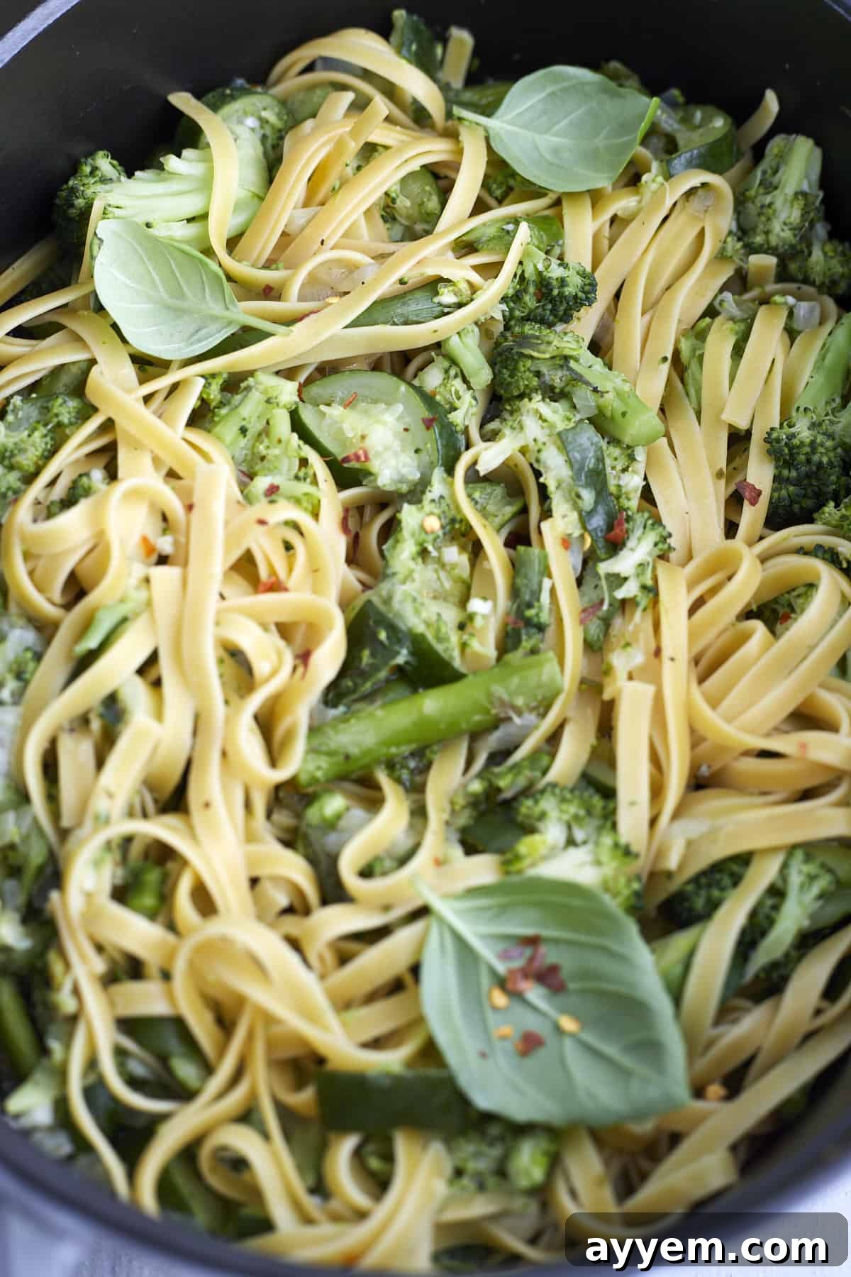 Close up image of one pot veggie pasta in a pot, showing the rich, creamy sauce coating the pasta and vegetables.