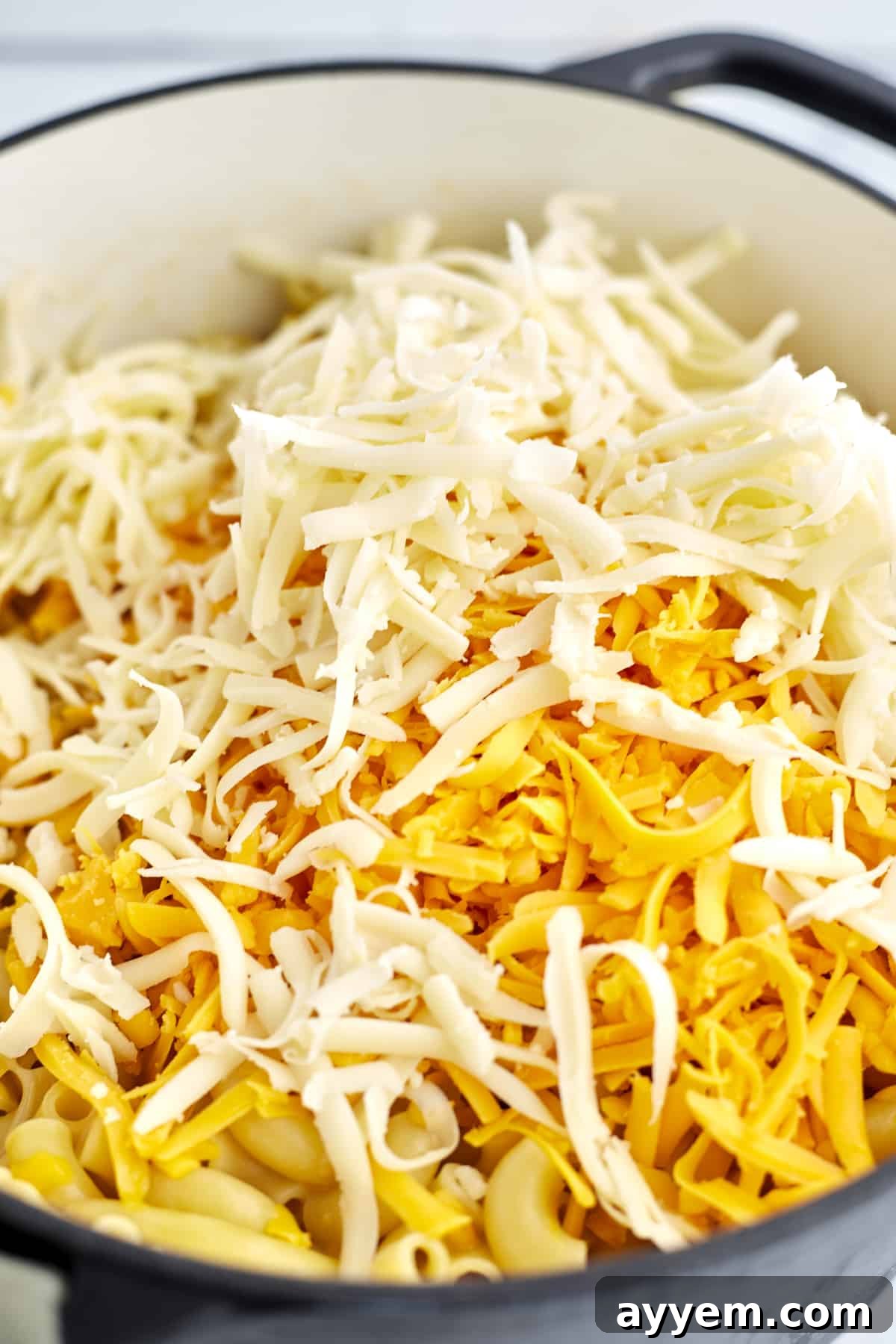 One Pot Wonder Mac and Cheese 4 a large pot of cooked elbow pasta topped with shredded Cheddar and Mozzarella cheese