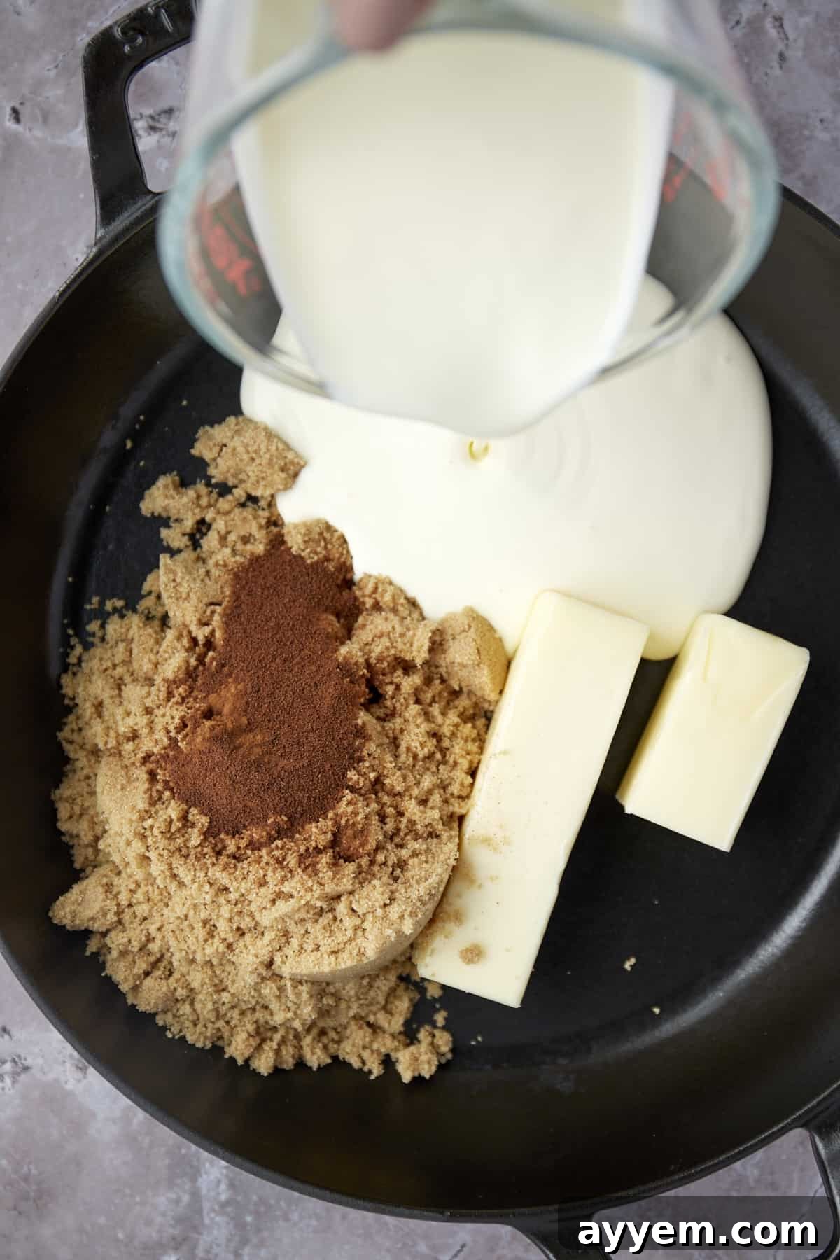 Ingredients for caramel macchiato sauce: brown sugar, butter, and heavy cream being poured into a saucepan.
