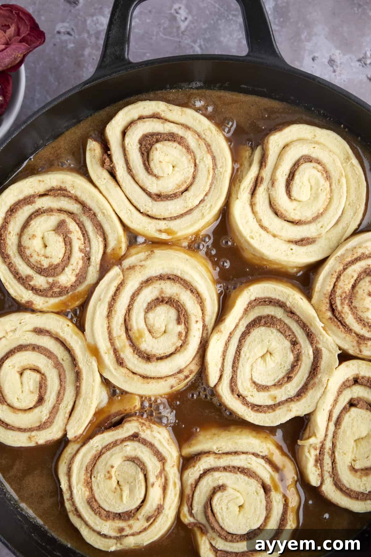 Raw cinnamon rolls arranged in a bundt pan, partially covered with rich caramel sauce.