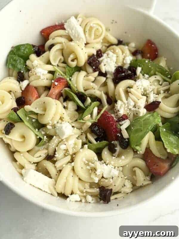 A bowl of summer pasta salad with fruit.
