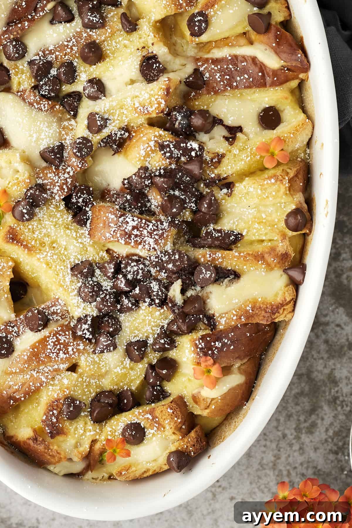 Ricotta Cream French Toast Bake 5 Freshly baked cannoli baked french toast in a dish, topped with melted chocolate chips and a dusting of powdered sugar.