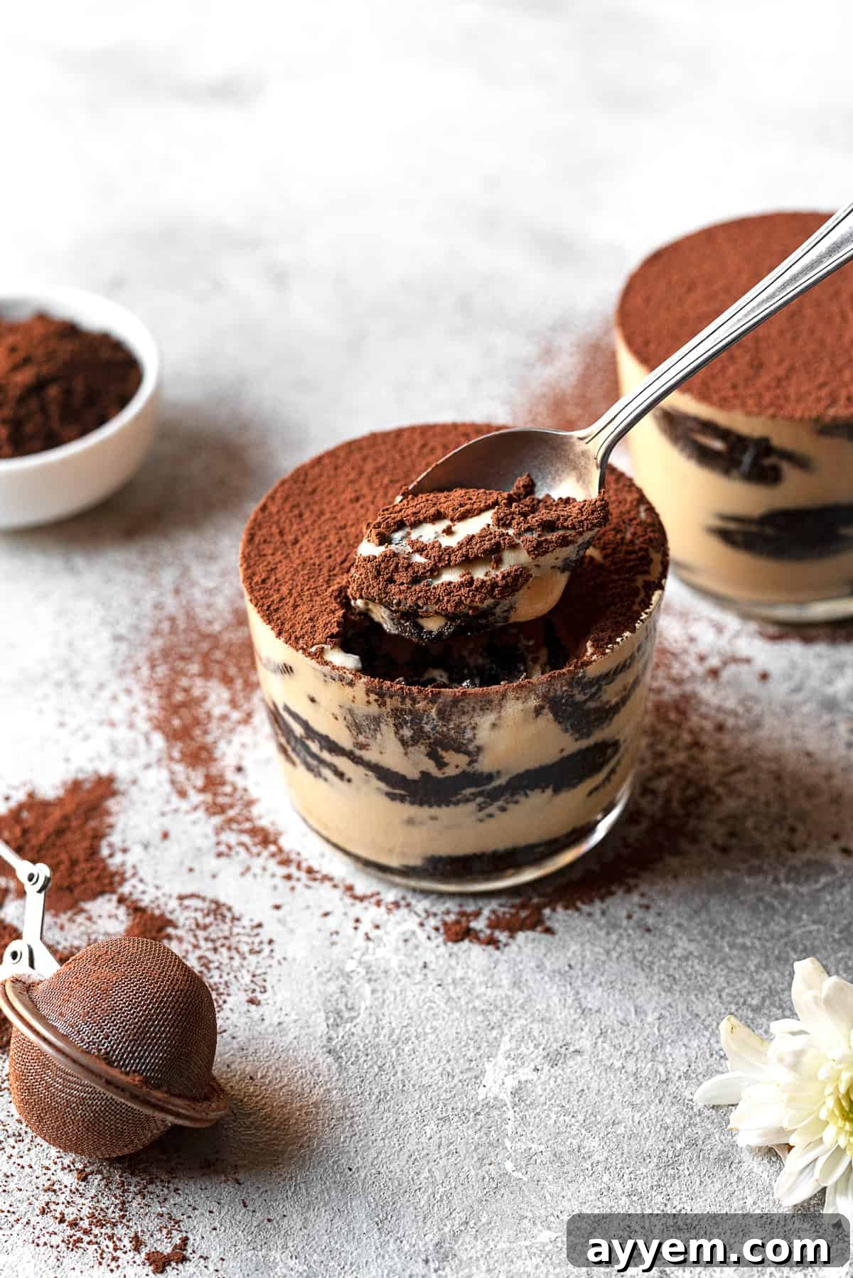 A spoon digging into a jar of Oreo Tiramisu, revealing the distinct layers of coffee-soaked Oreos and fluffy mascarpone cream.