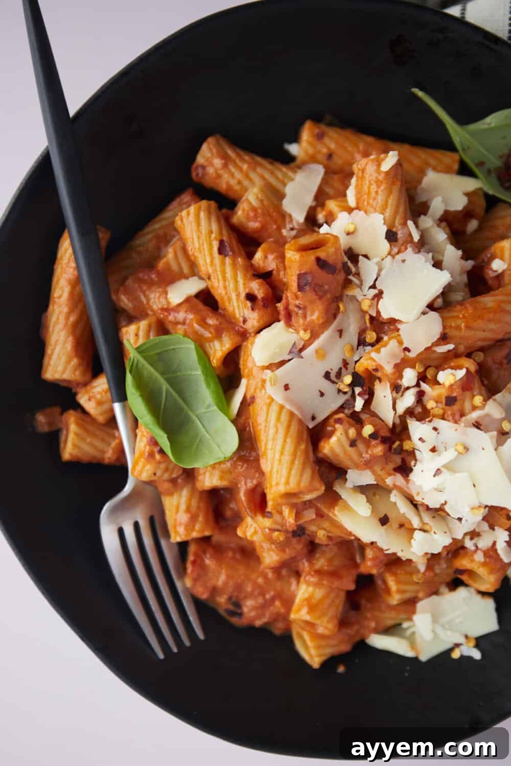 A tantalizing close-up of a bowl of spicy rigatoni pasta, with a fork resting casually on the side, inviting you to take a bite.