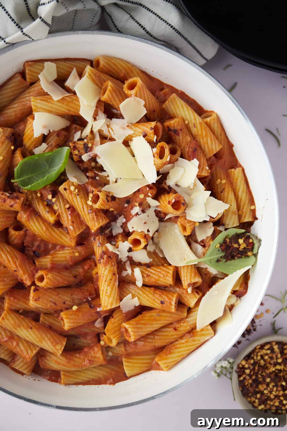 An overhead shot of a delightful bowl of spicy pasta, expertly topped with grated Parmesan cheese, showcasing its rich texture and appetizing appeal.
