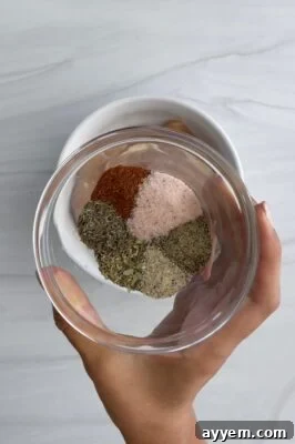 a woman's hand holding a glass bowl full of spices