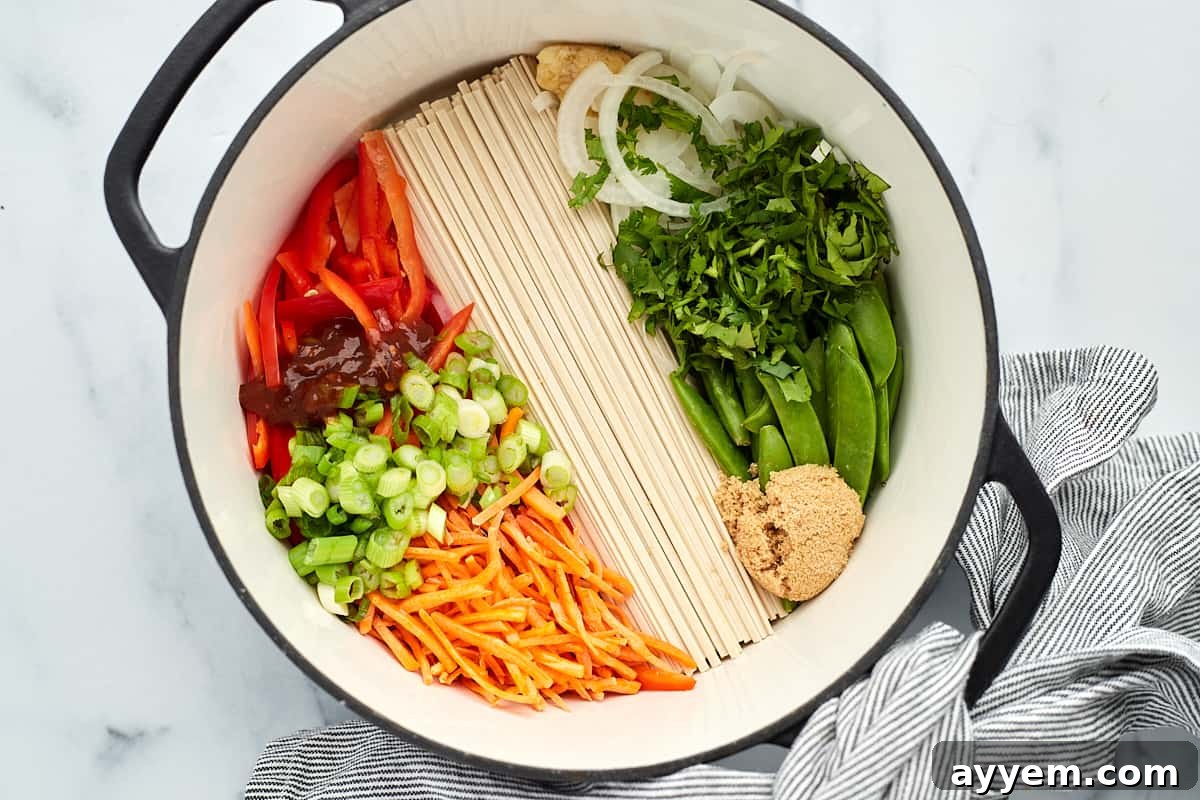 a pot full of veggies and rice noodles for ramen. 