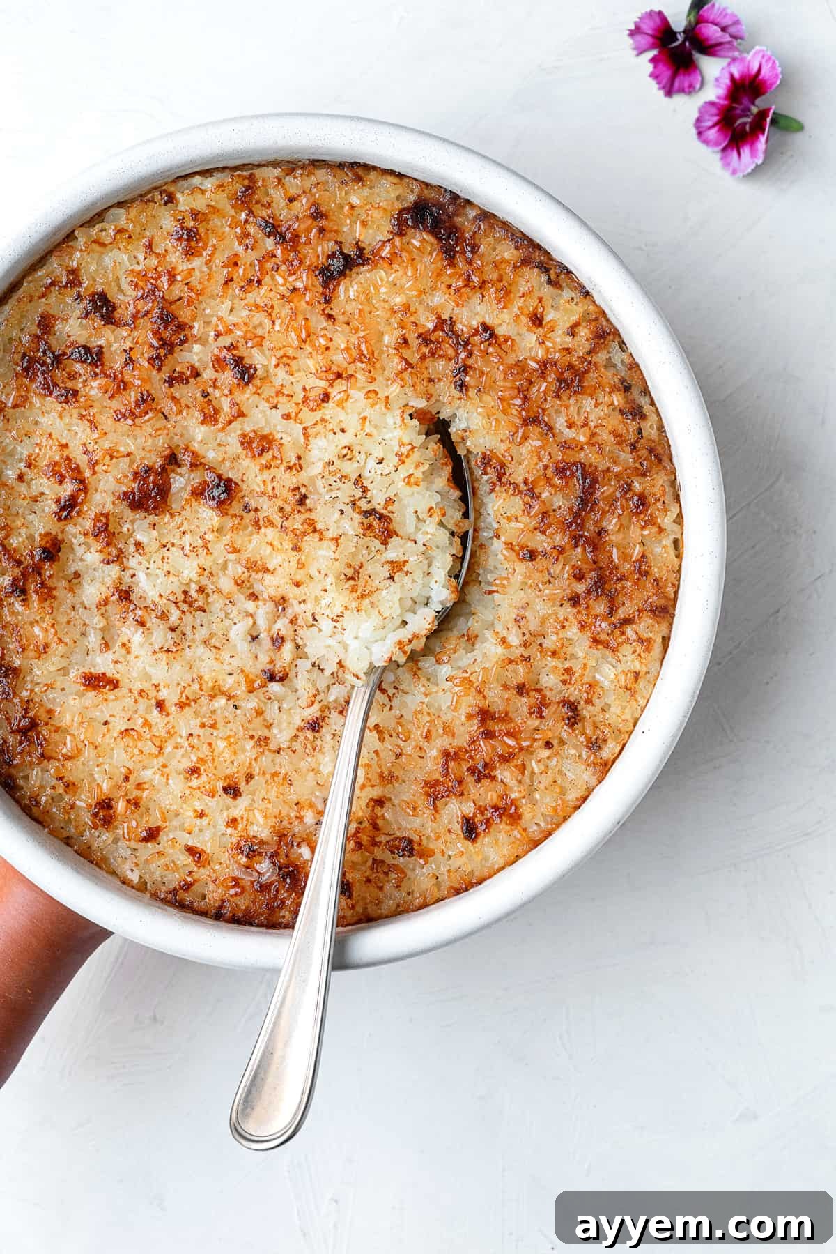A beautifully presented bowl of Egyptian baked rice, golden and creamy, with a spoon ready to serve.
