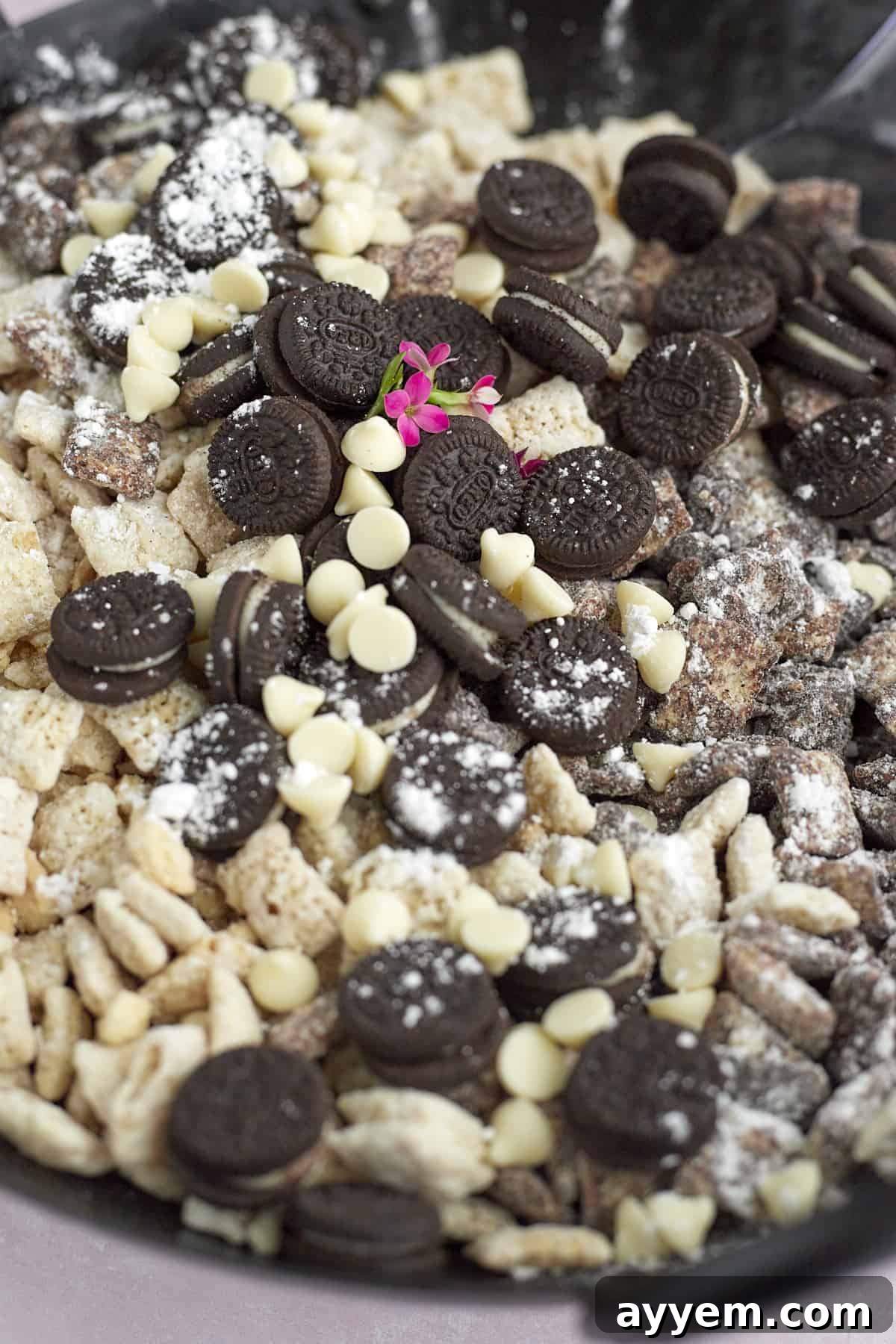 A close-up view of a pile of delicious cookies and cream muddy buddies, showcasing the various textures and chocolate coating.